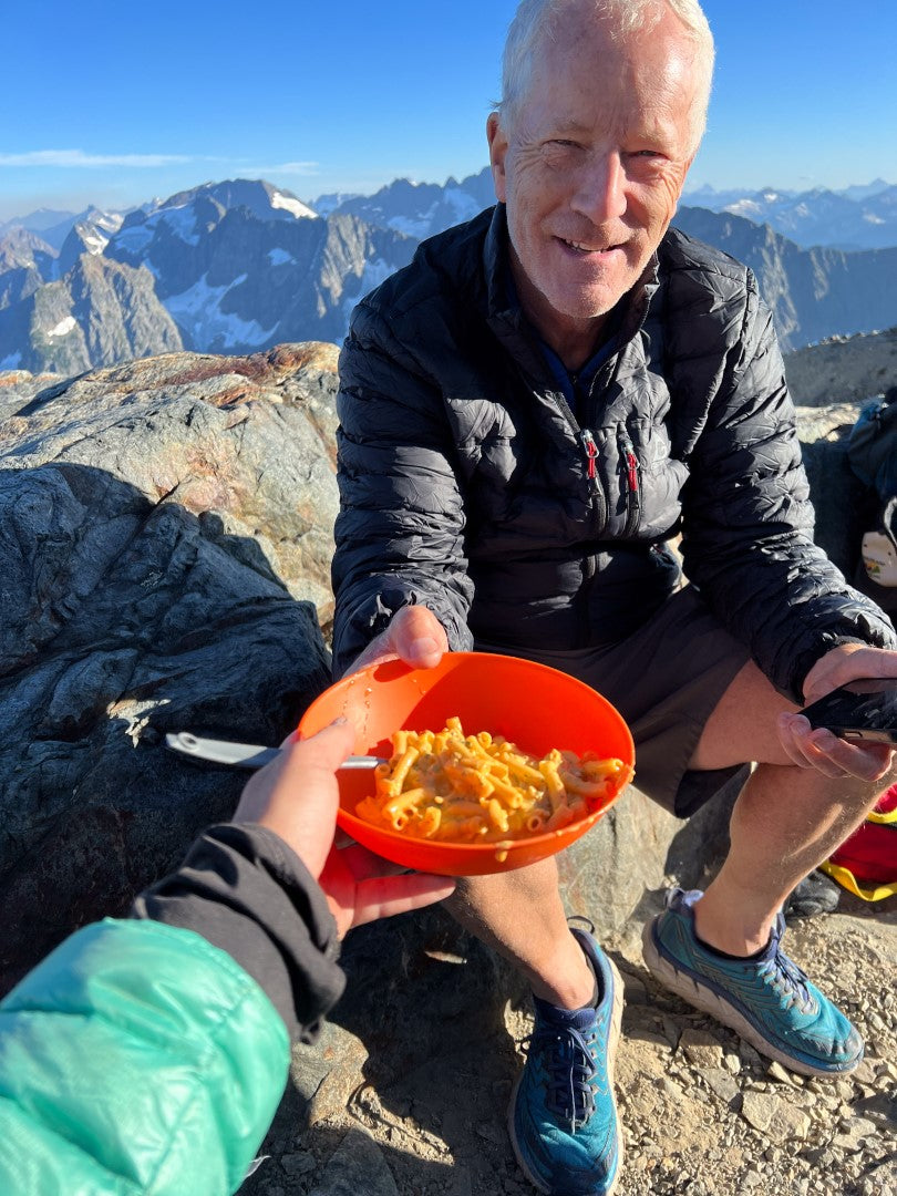 Two people sharing RightOnTrek Bechamel Mac and Cheese on top of a mountain