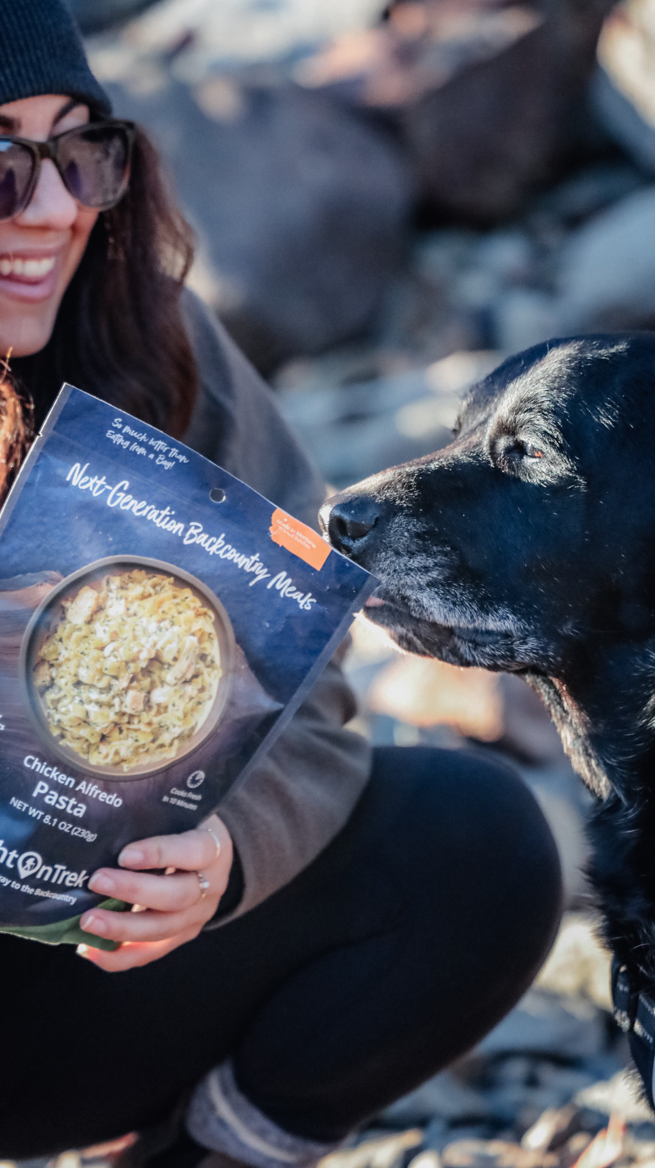 Happy hiker holding a backcountry meal with her dog